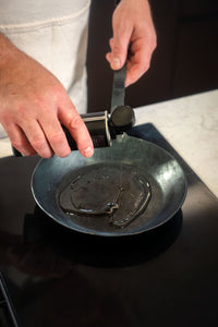 Jemand gießt Turk Bio Bratöl der Albert Turk GmbH & Co. KG in eine schwarze Bratpfanne auf dem Herd und macht sich bereit zum Kochen.