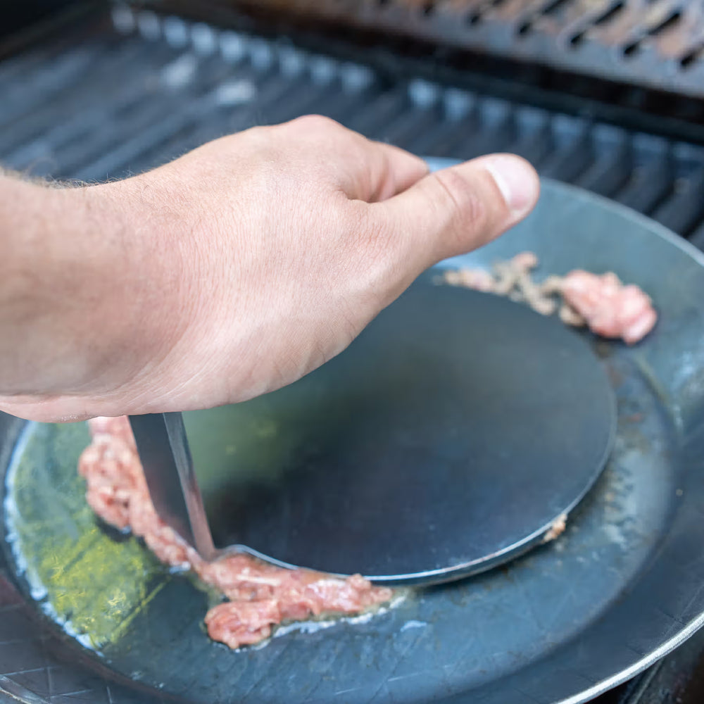 Hand presst mit dem Burger-Smasher von turk Hackfleisch zu einer Frikadelle auf einer Grillplatte