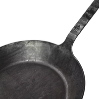 Nahaufnahme einer schwarzen Geschmiedeten Bratpfanne der Albert Turk GmbH & Co. KG, mit strukturiertem Griff und Haussymbol in der Nähe des Gelenks - ein elegantes Schaustück der Schmiedekunst, handgefertigt in Deutschland.